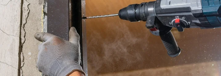 Person bohrt mit einem Akkuschrauber in einen Fensterrahmen